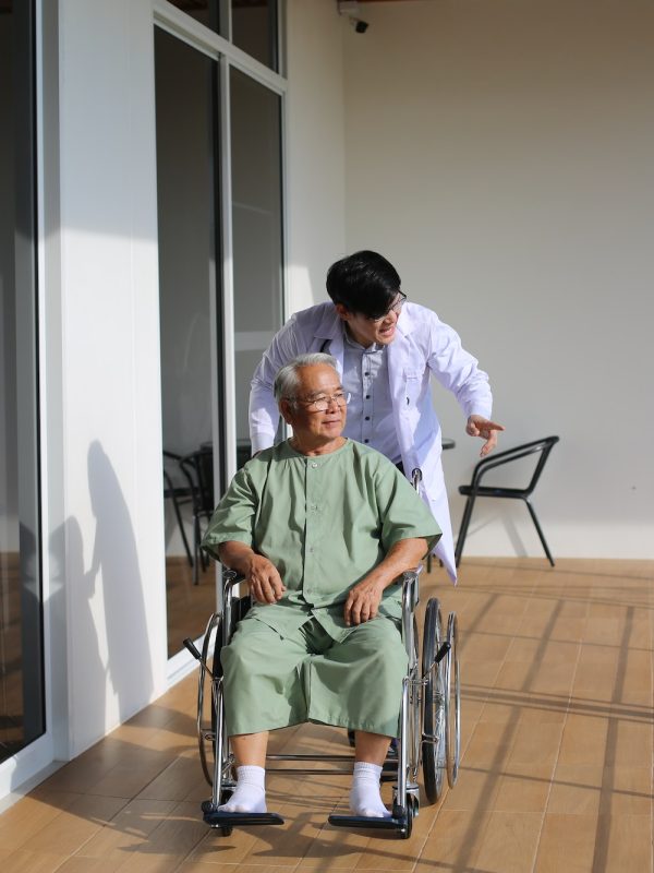 caretaker-helping-senior-man-with-disability-at-checkup-visit.jpg