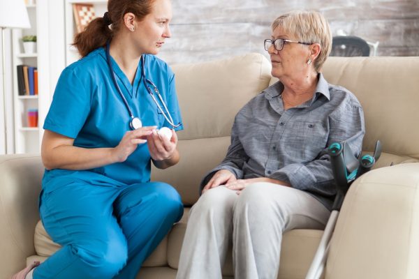 female-nurse-sitting-on-couch-with-senior-woman.jpg